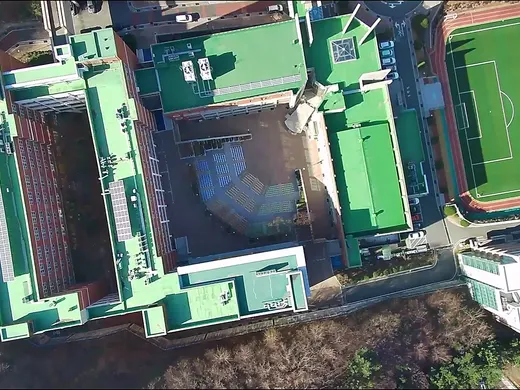 An overhead campus view with buildings and an athletics field.
