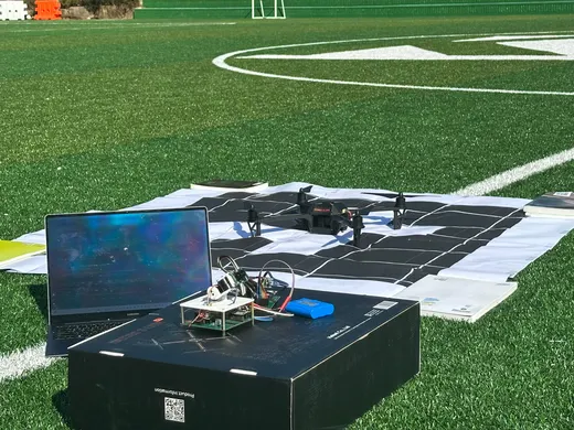 Drone and laptop prepared for a test on a playing field.